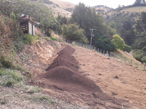 beds filled and covered in topsoil, and then capped with super-grow mulch, the remaining topsoil spread loosely over the rest of the cut