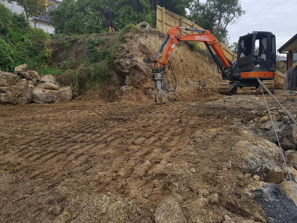 Excavator rock breaking during hard-ground hillside excavation Christchurch